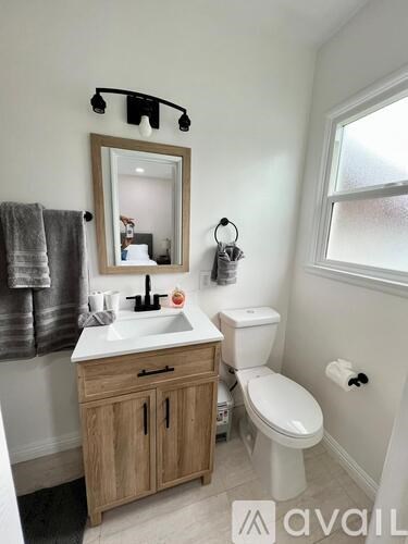 A bathroom with a toilet, sink, and mirror.