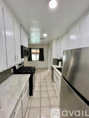 A kitchen with white cabinets and a stainless steel refrigerator.