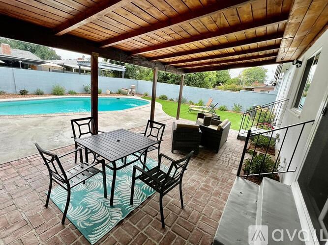 A patio with a table and chairs overlooking a pool.