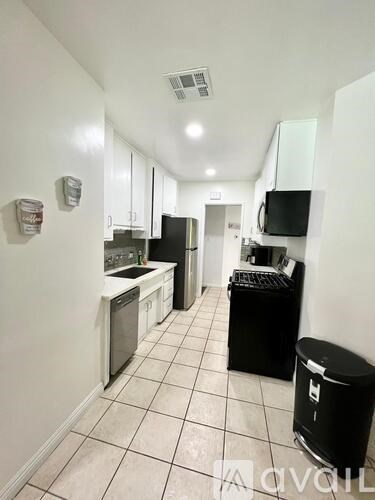 A kitchen with white cabinets and black appliances.