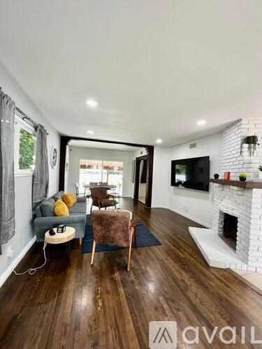 A living room with a white fireplace and wooden floors.