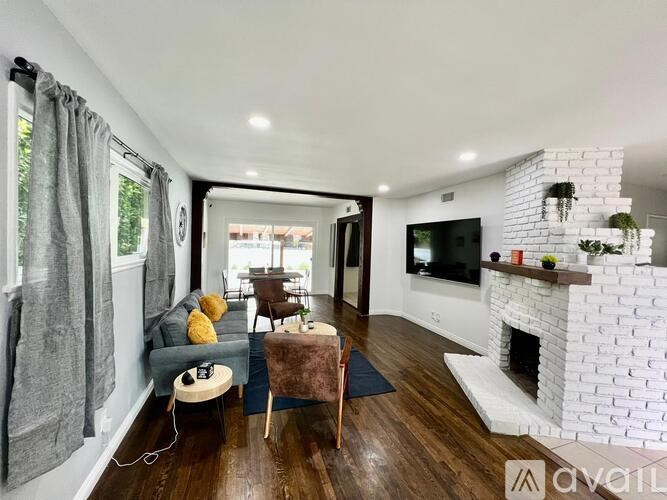 A living room with a grey couch, a white fireplace, and a TV mounted on the wall.
