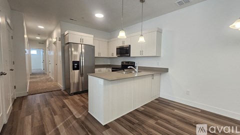 A kitchen with white cabinets and a wooden floor.