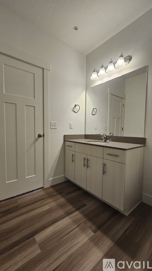 A bathroom with a vanity, mirror, and lighting fixtures.