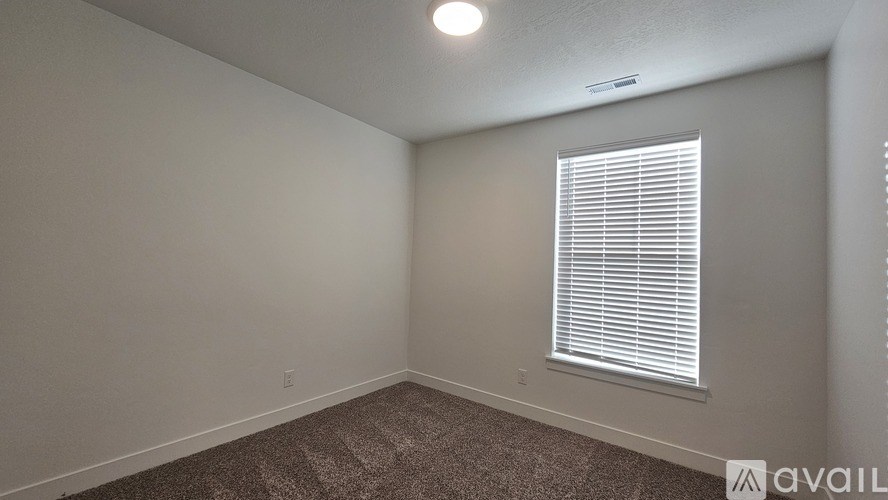 A room with a carpeted floor and a window with blinds.