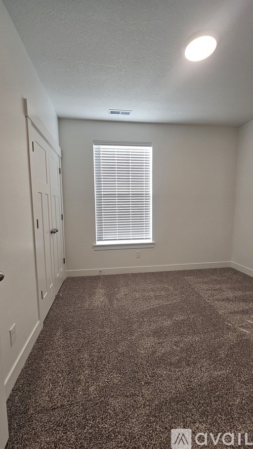 A room with a carpeted floor and a window with blinds.