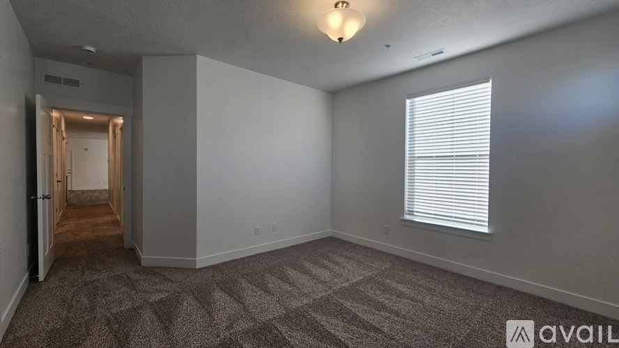 A room with a carpeted floor and a window with blinds.