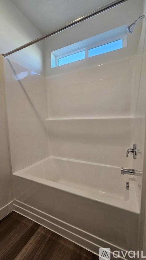 A white bathtub with a window above it.