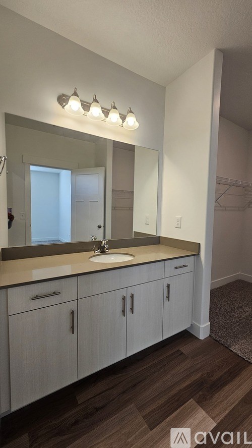 A bathroom with a sink, mirror, and cabinets.