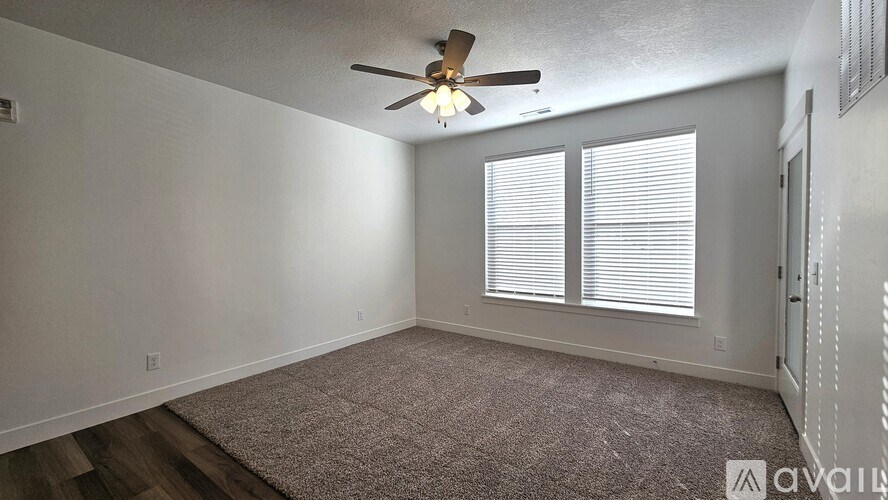 A room with a ceiling fan and carpeted floor.