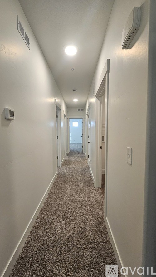 A long hallway with a carpeted floor and white walls.