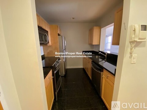 A kitchen with wooden cabinets and black countertops.