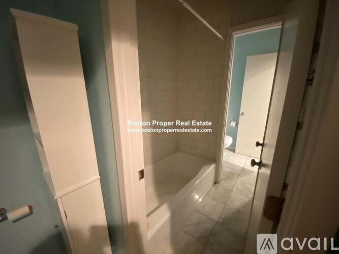 A bathroom with a white door and a white bathtub.