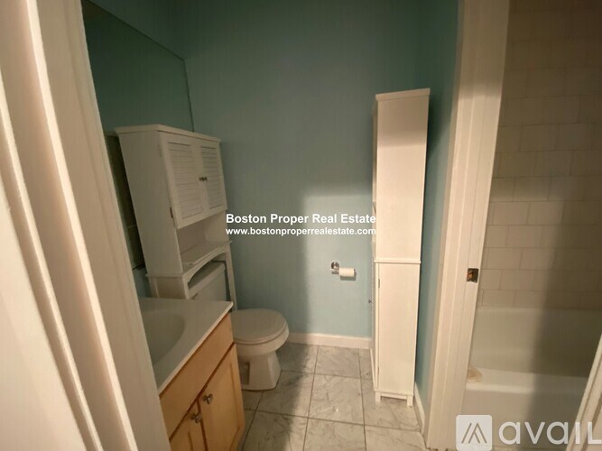 A small bathroom with a toilet, sink, and cabinet.