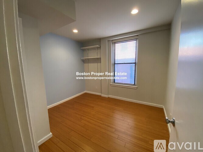 A room with wooden flooring and a window with blinds.