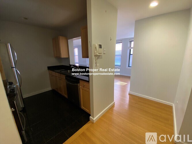 A kitchen area with wooden floors and a refrigerator.