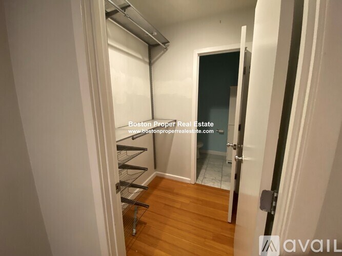 A hallway with a door on the right and a shelving unit on the left.