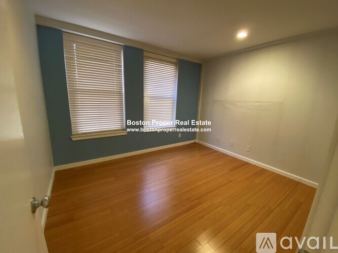 A room with wooden flooring and a window with blinds.