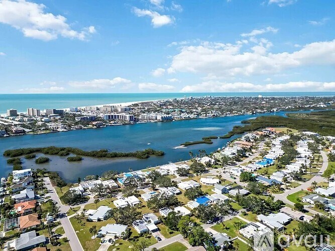 A bird's eye view of a residential area with a body of water in the foreground.
