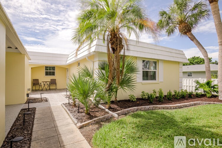 A white house with a palm tree in front.