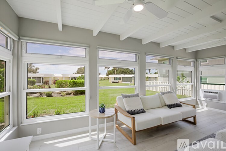 A sunny day in a living room with a white couch and a table.