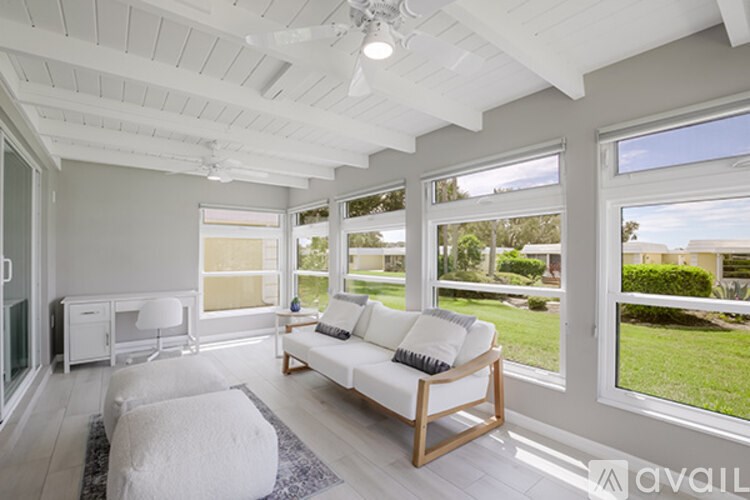 A sunny day in a living room with a white sofa and a rug.