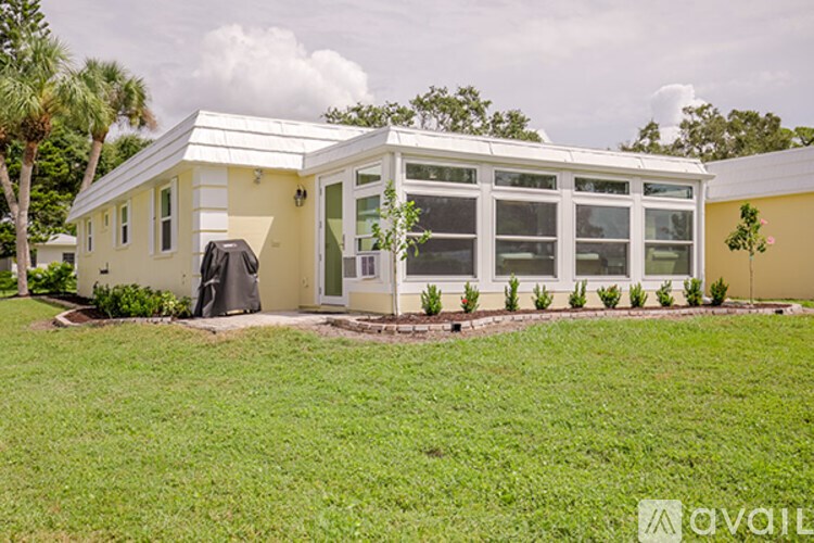 A yellow house with a white roof and a black trash can in front of it.
