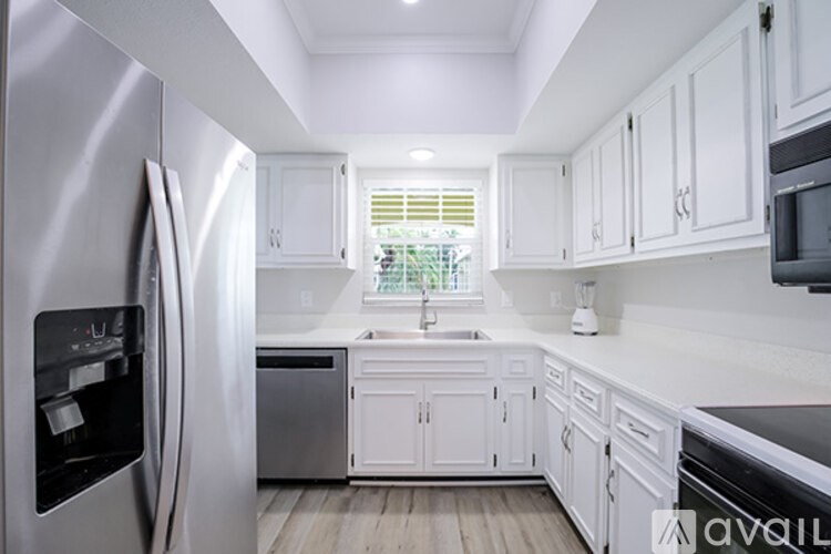 A kitchen with white cabinets and a stainless steel refrigerator.