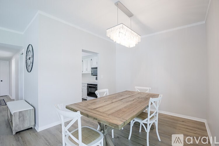 A dining area with a wooden table and white chairs.