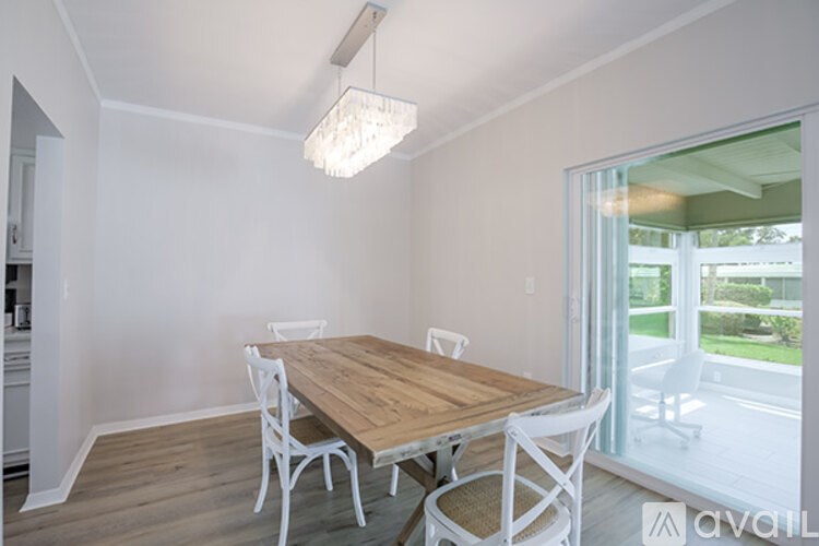 A dining room with a wooden table and white chairs.