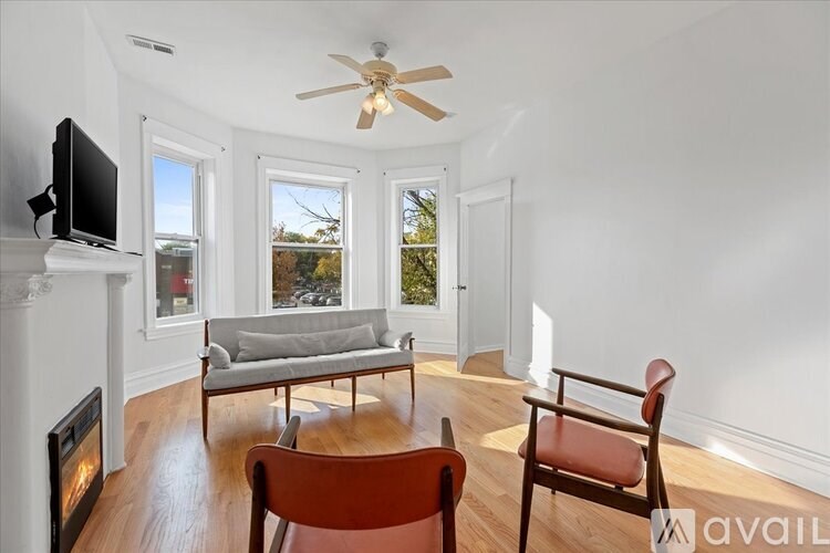 A living room with a fireplace, a grey couch, and a wooden chair.