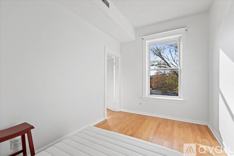 A room with a window and a wooden floor.