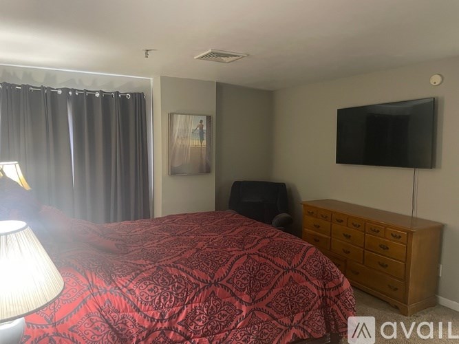 A bedroom with a red bedspread and a black television.