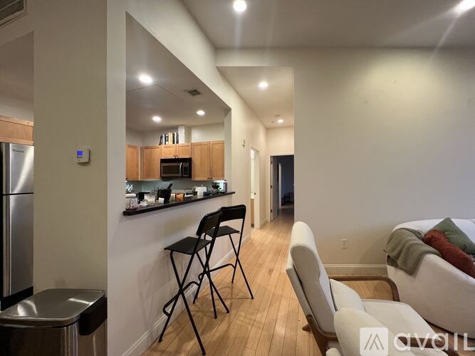 A kitchen with a refrigerator, a table with chairs, and a couch.
