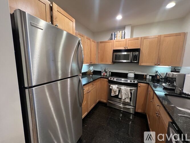 A kitchen with a stainless steel refrigerator and wooden cabinets.