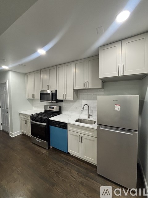 A kitchen with white cabinets and a stainless steel refrigerator.