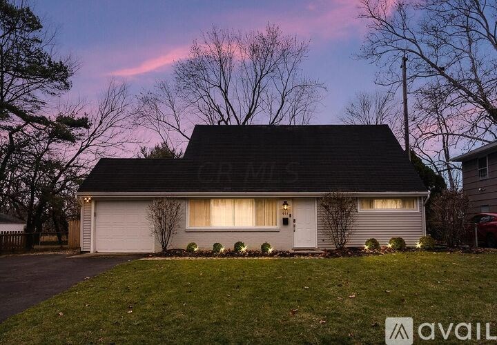 A house with a driveway and a tree in front.