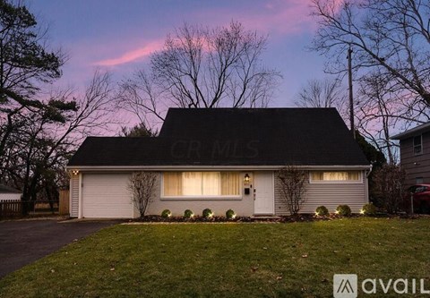 A house with a driveway and a tree in front.