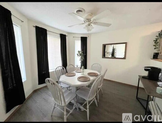 A dining room with a white table and chairs.