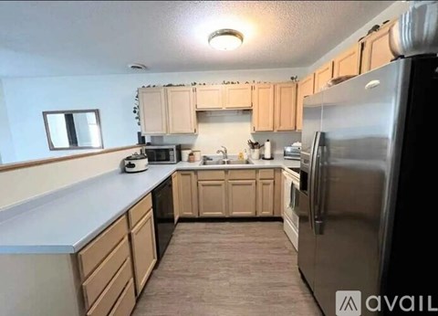 A kitchen with wooden cabinets and a stainless steel refrigerator.