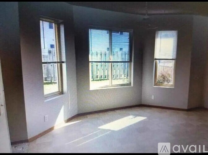 A room with three windows and a white floor.
