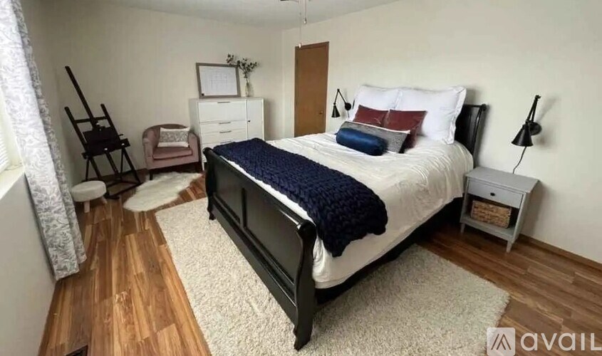 A bedroom with a bed, nightstand, chair, and a dresser.