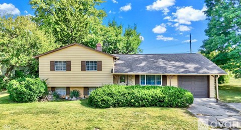A yellow house with a grey garage door and a grey roof.