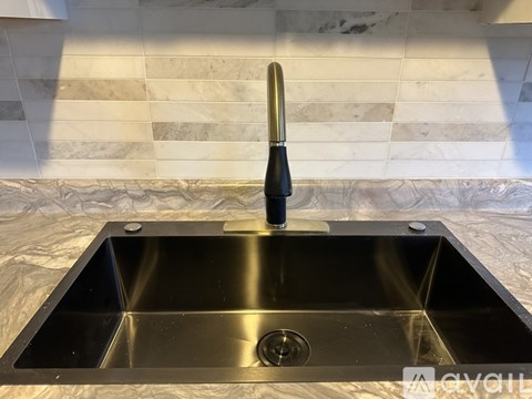 A stainless steel kitchen sink with a black faucet.