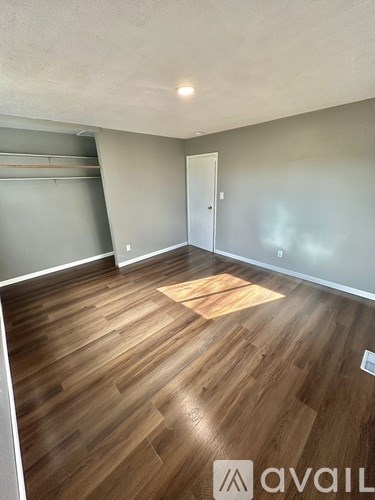 A room with wooden flooring and a door on the right side.