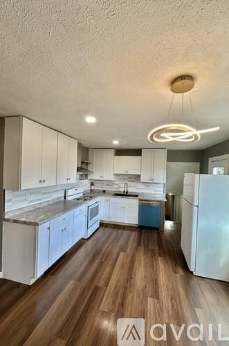 A kitchen with white cabinets and a wooden floor.
