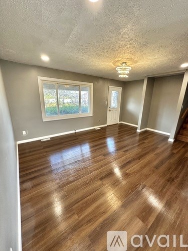 A room with wooden flooring and a window.