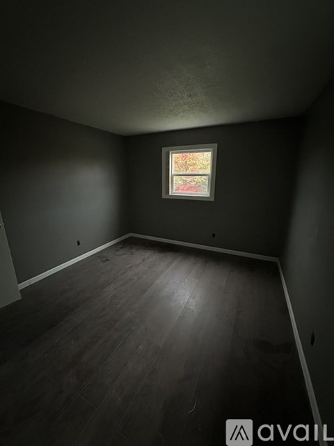 A room with a window and wooden flooring.