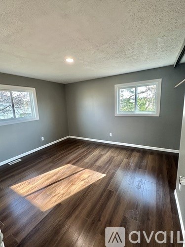 A room with wooden flooring and a door in the background.
