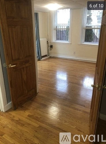 A room with wooden floors and a door on the left.
